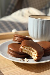 Tasty choco pies and cup of hot drink on wooden tray