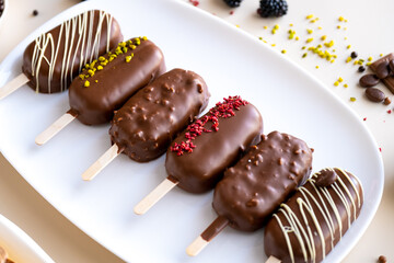 Chocolate biscuits on a stick in the form of ice cream.Appetizing cupcakes and pastries.cupcake ice cream with chocolate cream.Choux pastry. Chocolate cupcakes set on a white plate. 