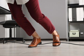 Woman tripping over cable in office, closeup