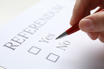 Woman with referendum ballot making decision on white background, closeup
