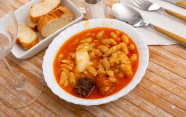 Hearty beans stew with pork, blood sausage and chorizo served in white bowl. Traditional dish of...