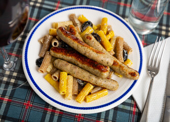 Delicious rigatoni with olives in creamy sauce served with roasted sausages. Italian dish..
