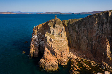Fototapeta na wymiar Two sea stacks in the sea. Abandoned lighthouse on top of a rocky island