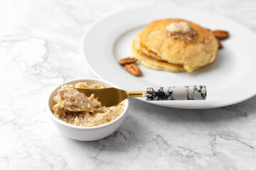 Pecan Butter in a White Bowl with Pancakes out of focus in background