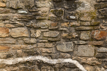 Close up of old stone wall with thick grout and rough textured surface.