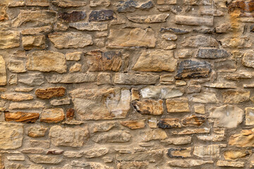 Close up of old stone wall with thick grout and rough textured surface.