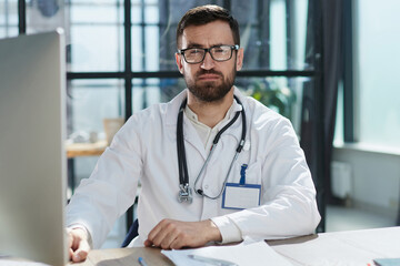 Doctor working with laptop computer and writing on paperwork. Ho