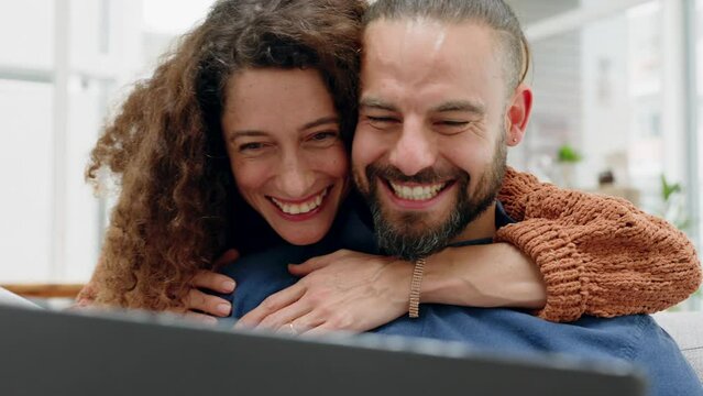 Support, excited and love with couple good news reading from laptop in living room at home together. Celebration, hug and relationship with married man and woman embrace for happy message or email