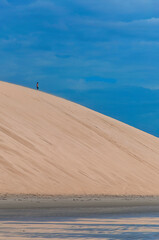 Man standing on top of a giant dune by the sea in Jericoacoara