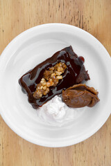 Sweet desserts. Top view of a bittersweet chocolate flan with vanilla cream and dulce de leche, in a white dish on the wooden table. 
