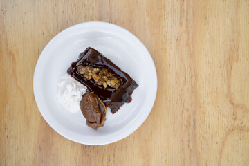 Sweet desserts. Top view of a bittersweet chocolate flan with vanilla cream and dulce de leche, in a white dish on the wooden table.