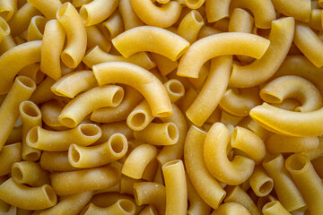 Uncooked and dry macaroni textured background, food macro close-up background.