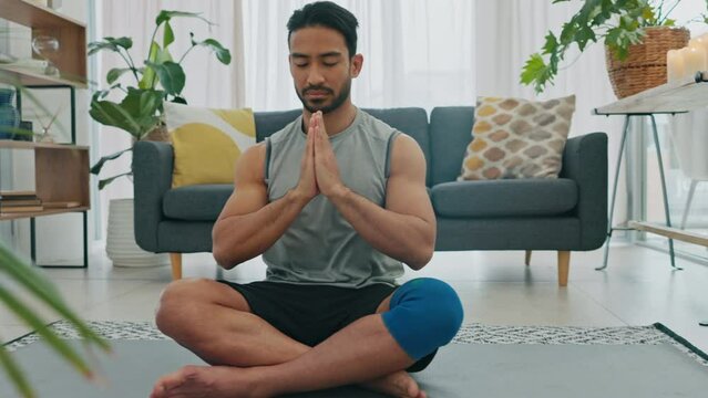 Meditation, yoga or zen asian man in relax, peace and mental health training, workout or exercise in house living room. Prayer hands, worship or reiki mind energy support in wellness lockdown fitness