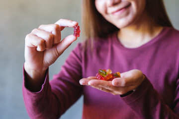 Closeup image of a young woman holding and showing at a red jelly gummy bears