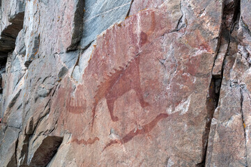 An ancient Indigenous pictograph is painted on a rock face on a cliff at the side of Lake Superior...