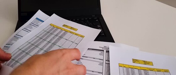 Slow motion footage of a person checking balance sheet and loan amortization table. Finance