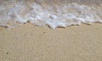 white waves on a quiet beach with soft brownish sand