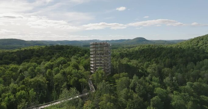 Beautiful wooden tower hiking trail. Mountains and trees. Wide landscape. Marvelous sunny summer day. 4k UHD drone circling structure. far point of view. Professional pilot.