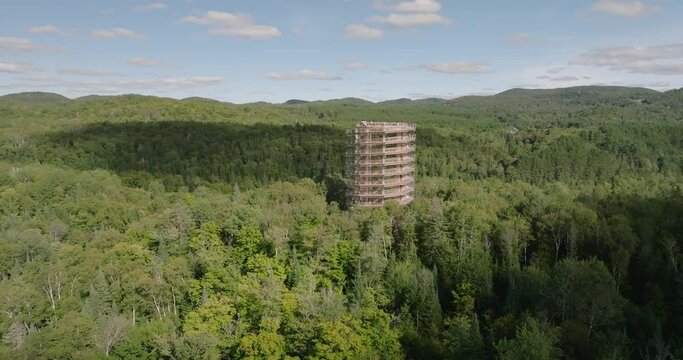 Beautiful wooden tower hiking trail. Mountains and trees. Wide landscape. Marvelous sunny summer day. 4k UHD drone circling structure. far point of view. Professional pilot.