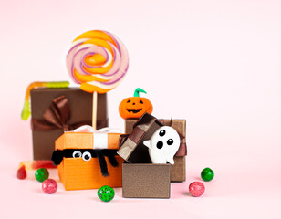 Obraz premium gift boxes with halloween symbols, lollipops and candies on a pink background close-up