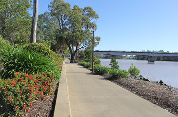 View of the Rockhampton waterfront with plants, walkway, trees, Fitzroy River and bridge in Queensland, Australia - obrazy, fototapety, plakaty