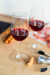 Two glasses of red wine with charcuterie, cheese, grapes and snacks