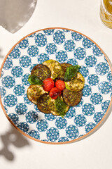 Grilled vegetables on light background with shadows. Salad with grilled zucchini, eggplant and tomatoes. Aesthetic composition with bbq vegetables. Vegan food. Grilled vegetables in Summer menu.