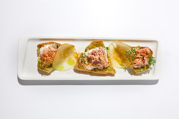 Aesthetic composition with crab bruschetta on white background over white wall. Italian bruschetta with crab, avocado and cheese on fine dining in summer. Elegant menu concept.