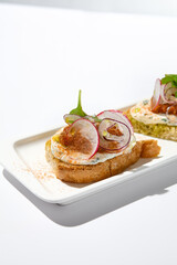 Aesthetic composition with tomato bruschetta on white background with harsh shadows. Italian bruschetta with tomatoes and cheese on fine dining in summer. Elegant menu concept.