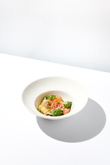 Elegant salad with crab meat, espuma sauce and lettuce on white table with harsh shadows. Green salad with crab and creamy sauce in summer menu. Aesthetic food. Seafood appetizer.