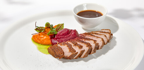 Roast duck fillet with vegetables puree and sauce on light background. Elegant dish from duck...