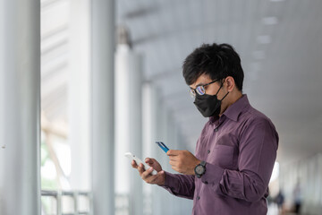asian Business man with surgical face mask using creadit card and smartphone.