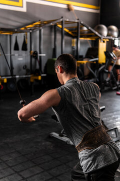 High quality photo. Caucasian man from behind training on a crossover. Man training chest.