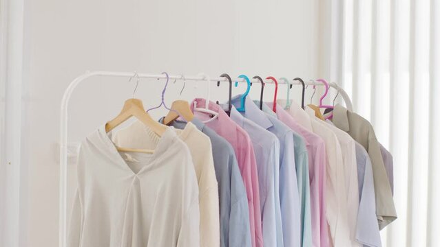 Woman dress and cloths hanging on hanger soft and pastel color in modern boutique. Colorful of collection of woman cloth hanging in closet in cozy room