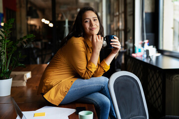 Young businesswoman drinking coffee in her office. Woman enjoy in coffee break..