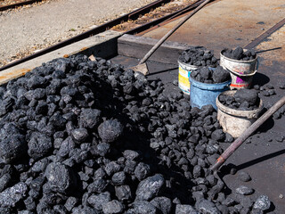 Pile of coal with shovels and buckets, ready for the steam train.