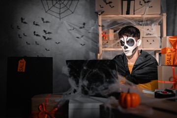 Drop shipping business owner wears white clay skull, professional makeup in home office. accepts an order on the site. Festive decorated office. Halloween sale concept, baner.