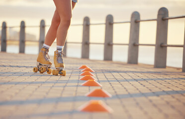 Woman roller skating with fitness cones outdoor on the promenade at the beach during summer. Girl...