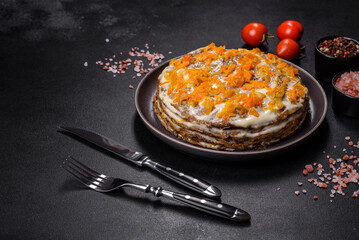 Delicious fresh liver cake with mayonnaise and carrots on a black plate against a dark concrete background