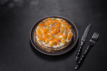 Delicious fresh liver cake with mayonnaise and carrots on a black plate against a dark concrete background