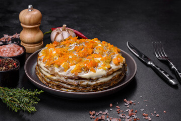 Delicious fresh liver cake with mayonnaise and carrots on a black plate against a dark concrete background