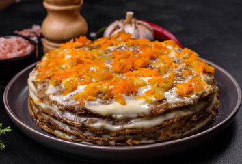 Delicious fresh liver cake with mayonnaise and carrots on a black plate against a dark concrete background