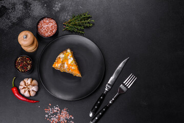 Delicious fresh liver cake with mayonnaise and carrots on a black plate against a dark concrete background