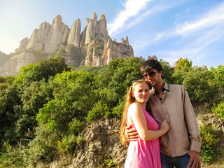 Young happy couple in the sunshine near the mountain of Montserrat in Catalonia, Spain. A nice long-haired blonde and a tall attractive man with black hair travel to an amazing mountain near Barcelona