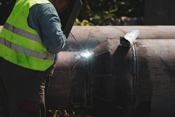 Shallow depth of field (selective focus) details with a professional welder welding an industrial...