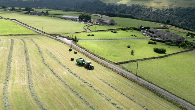 Green Tractor harvesting hay on a rural Yorkshire landscape aerial view. Nature scenery. Farming scene