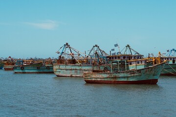 Obraz premium Fishing boats floating on the calm blue sea water in the Pamban island in Rameshwaram, Tamilnadu, India. Monsoon season fishing in India. Fishing boats in the harbor.