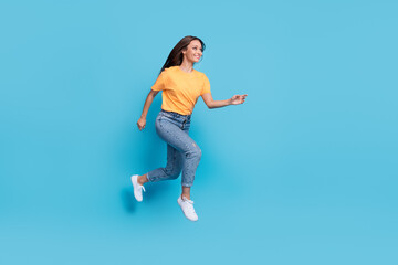 Fototapeta na wymiar Full length photo of shiny sweet girl dressed yellow t-shirt jumping high running fast empty space isolated blue color background