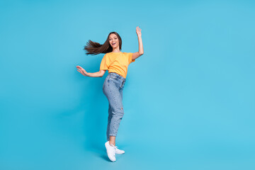 Fototapeta na wymiar Full length photo of excited sweet girl dressed yellow t-shirt having fun dancing empty space isolated blue color background