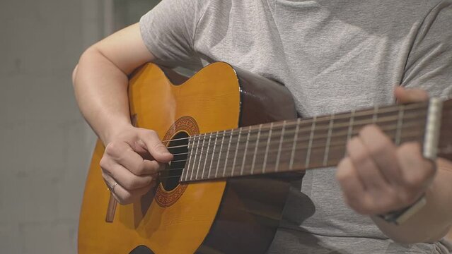 fingers tapping on the strings of a yellow acoustic guitar